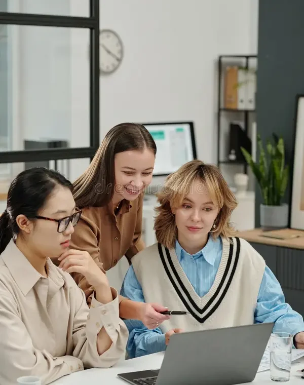 Three colleagues reviewing work on a laptop